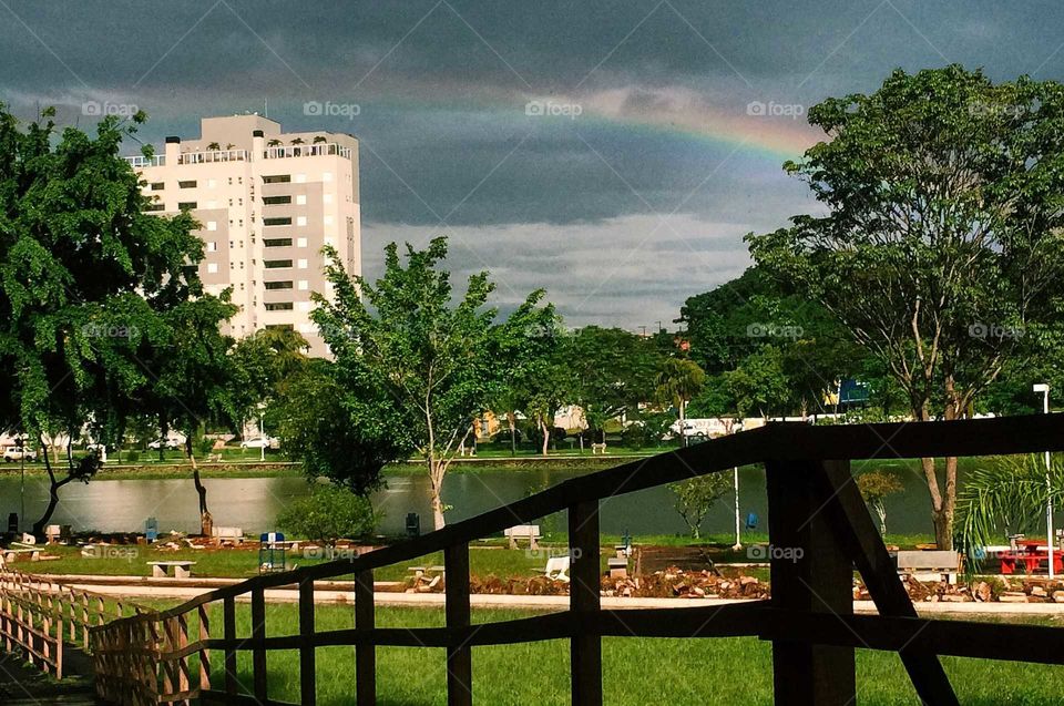 Beautiful shot of a landscape, a park with storm clouds and a rainbow above the lake of the park.