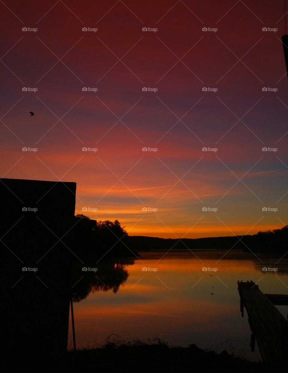 Silhouette of pier over lake during sunset