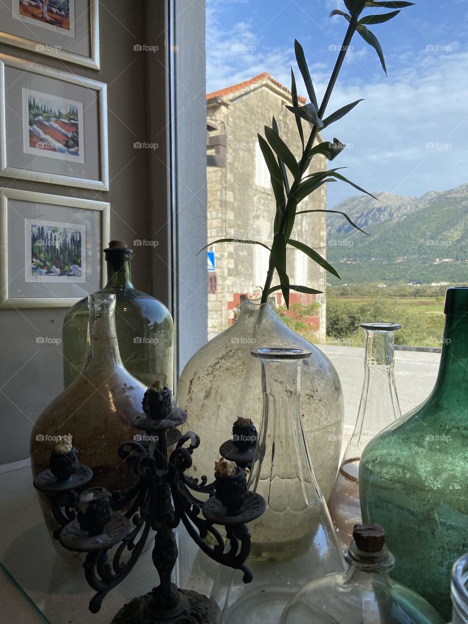 Colorful empty bottles near a window with a view.