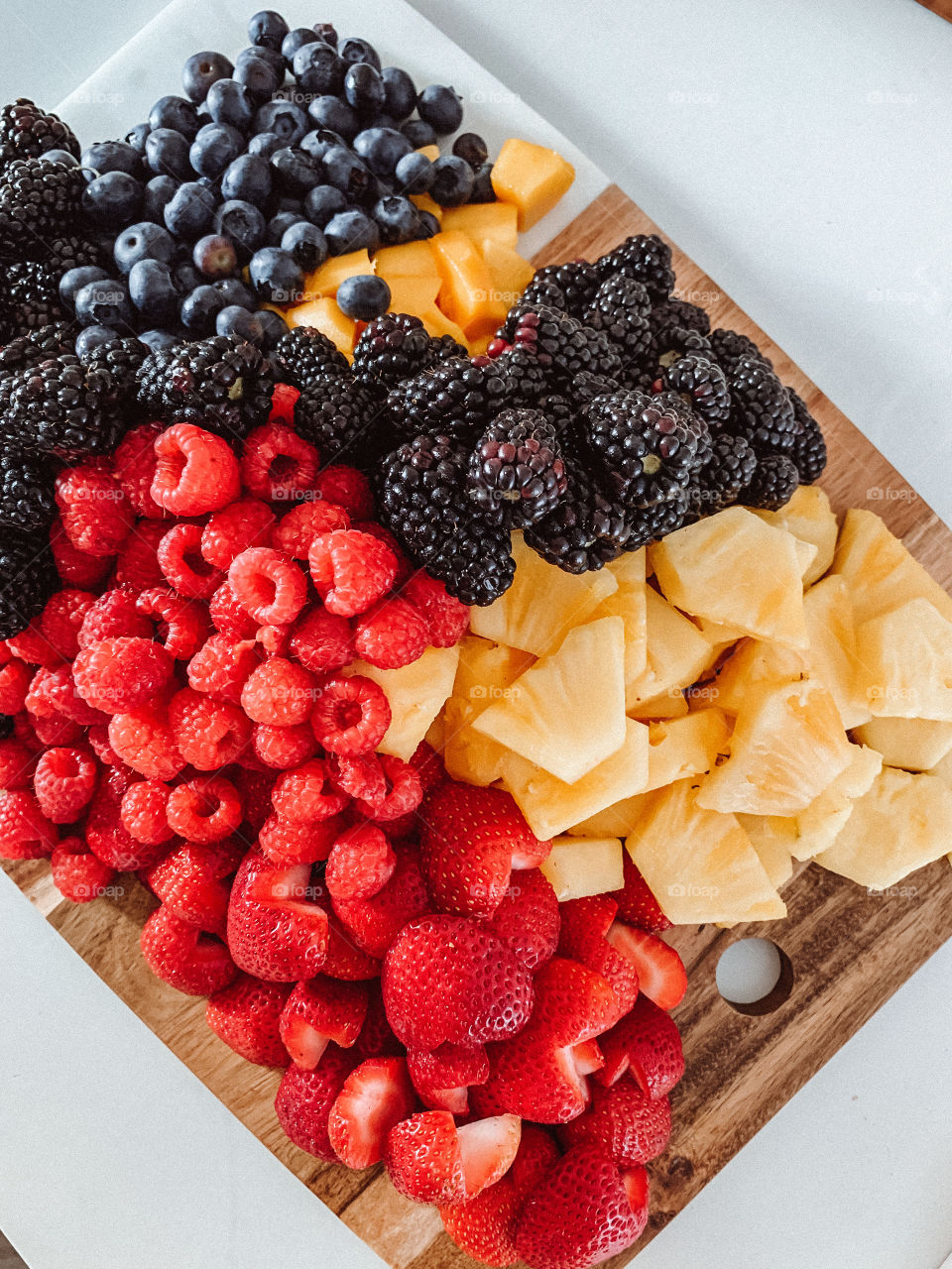 Fruit charcuterie board made with strawberries, pineapple, blackberries, mangoes and blueberries.