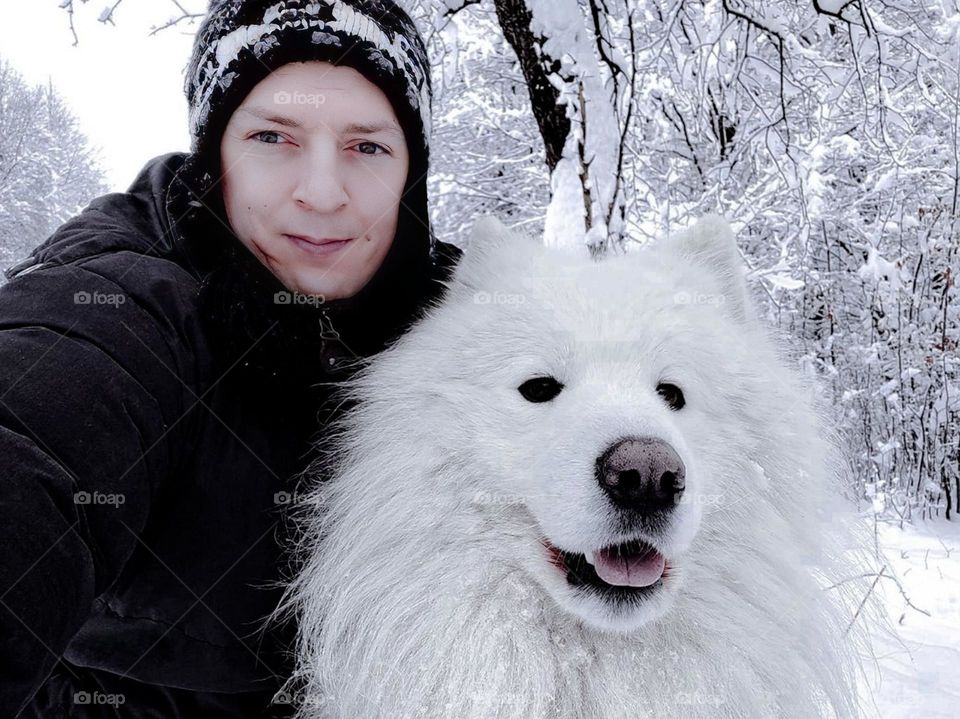 Close-up view of a person and a dog with thick white fur in a snowy setting