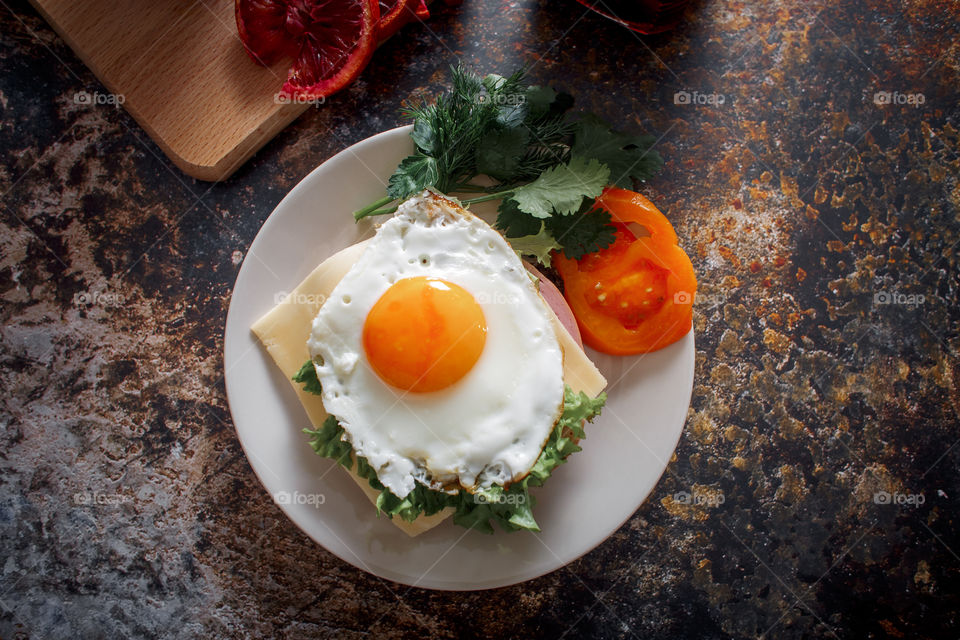 Sandwiches with fried egg orange tomato and red orange fruit 