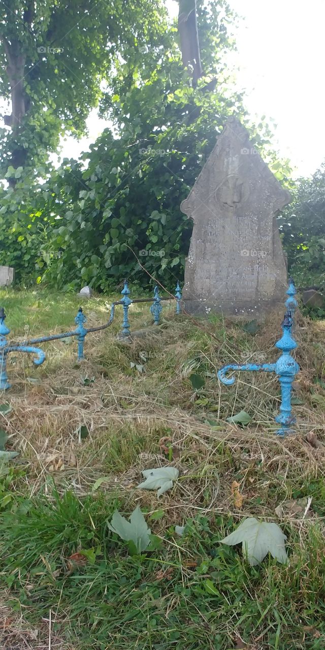 gravestone with broken blue metal rail