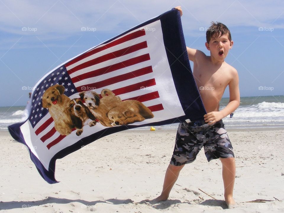 Boy holding beach towel in the wind