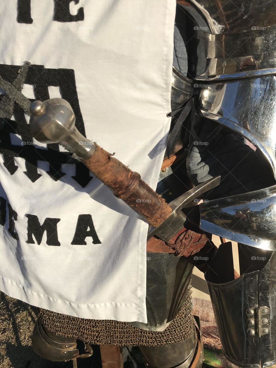 A sheathed Longsword suspended from a belt around the knightly armor display at the Kearney Park Renaissance Faire.