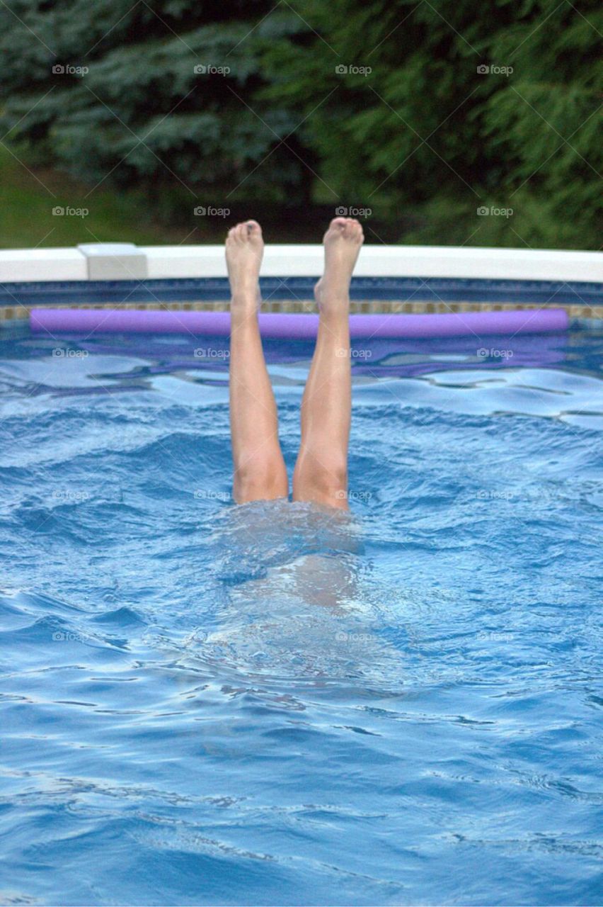 Young girl practicing her hand stands in the pool. 