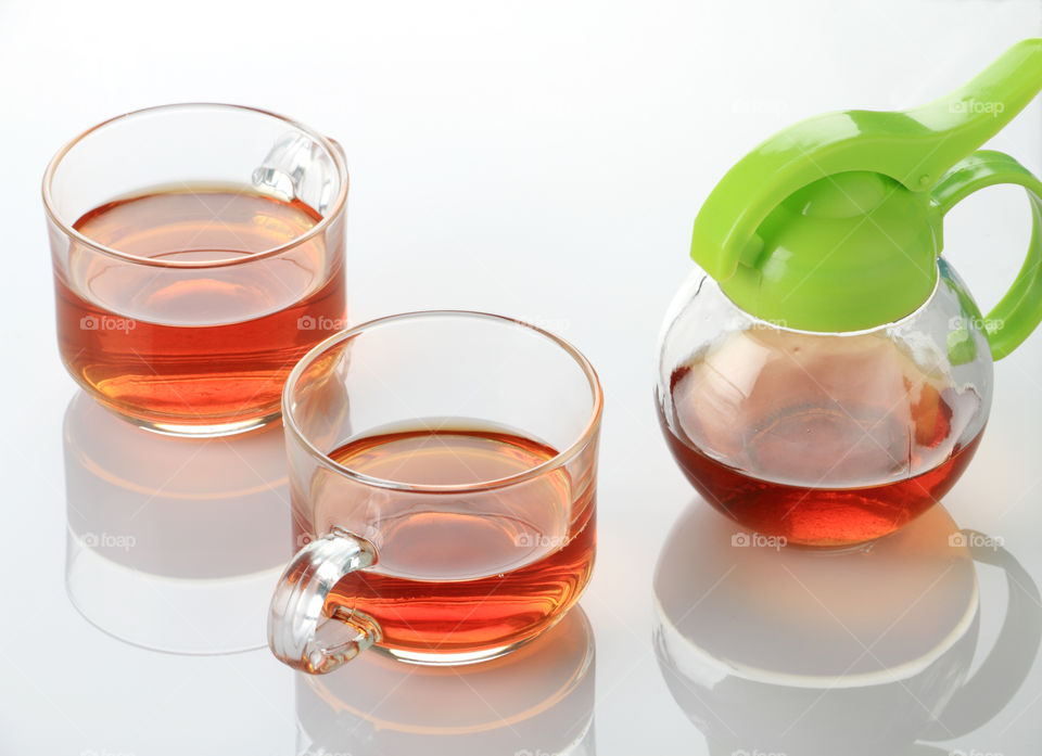 Cups of tea with a kettle on white reflective background