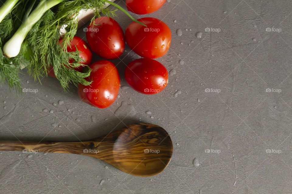 Fresh, bright, fragrant, farm vegetables with splashes of water on a gray table surface.