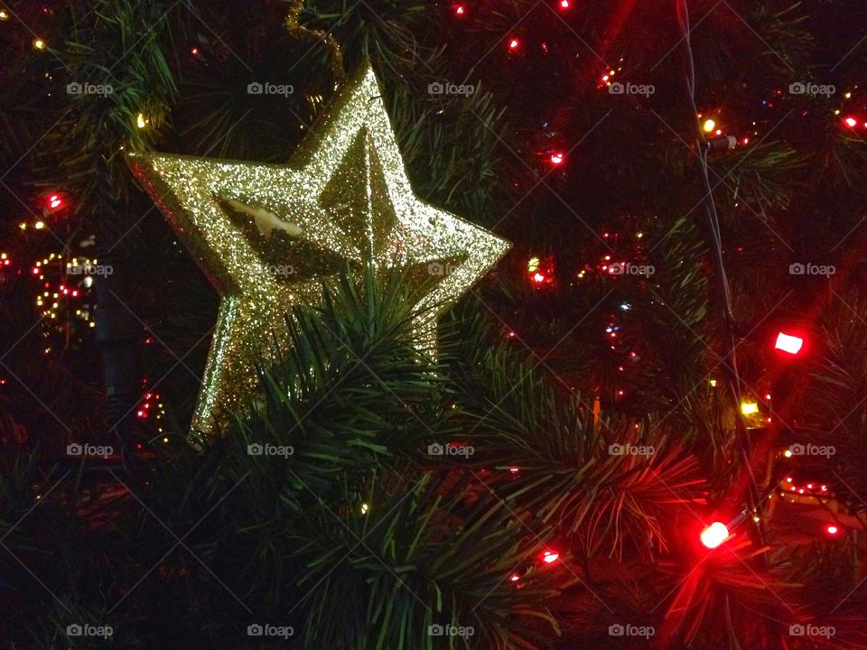 Gold plastic star, balls, red lights garland and other Christmas decorations on artificial fir tree in Moscow, Russia