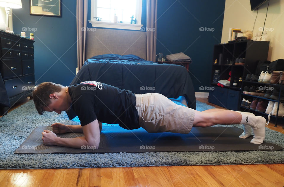 Young man performing plank, yoga at home