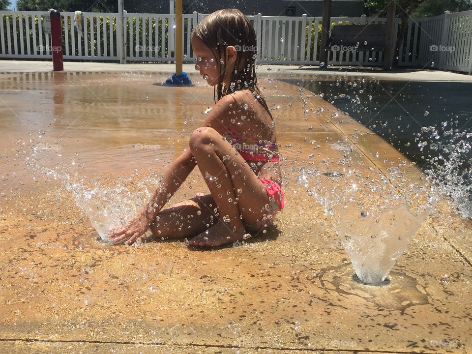 Little girl playing at the water park 