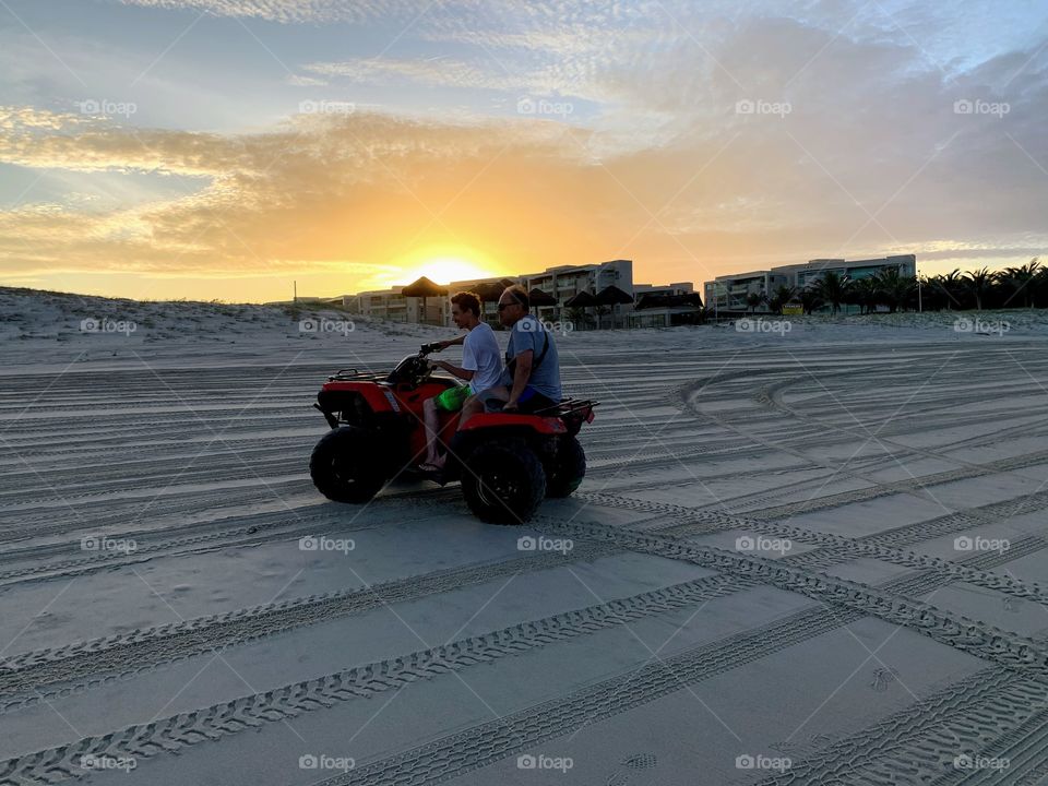 Father and son riding a quad on the beach in Aquiraz, Brazil