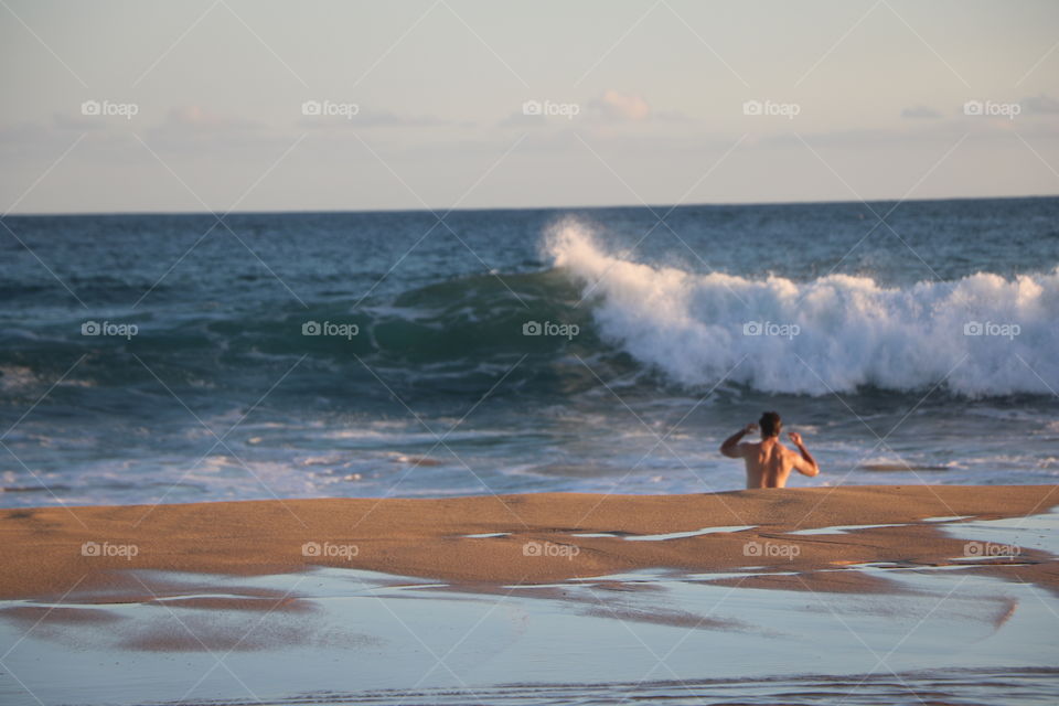 Young man and a big wave coming - he is calculating its speed , would he jump  or dive in... well he did jump ..