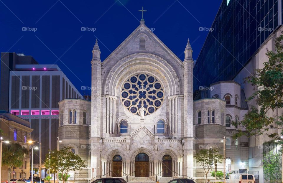 beautiful church with a large rosette window focal point and beautiful architectural design elements against a royal blue evening sky