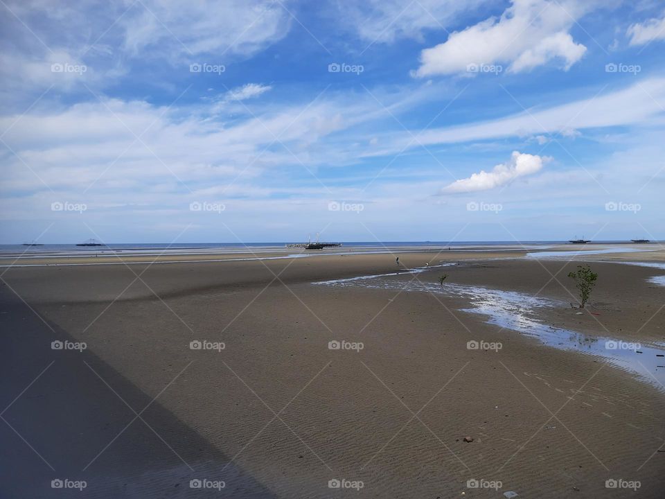 the beach is receding under the blue summer sky