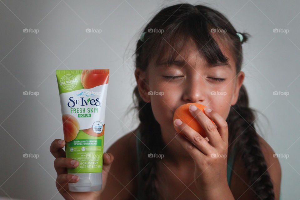 Cute girl is smelling apricot and St.Ives body scrub