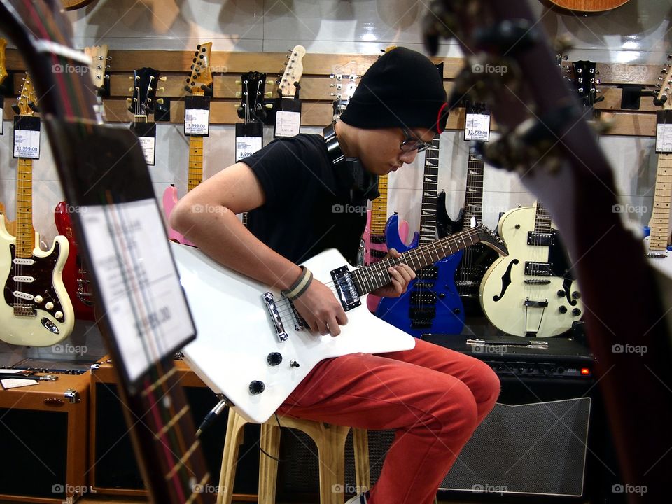 male teenager playing guitar in a guitar store