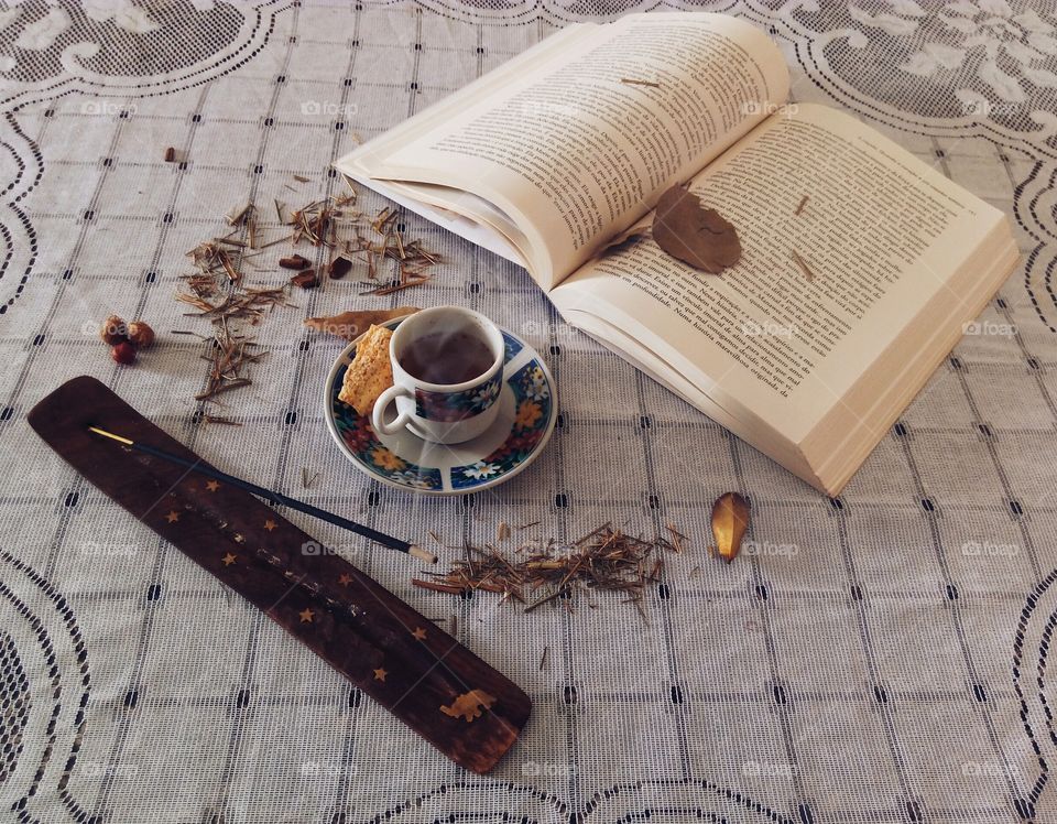 Book, tea and incense stick on table