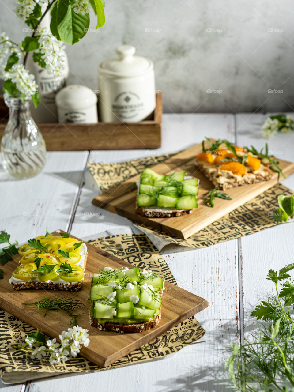 Wholegrain bread slices on wooden boards topped with veggies and herbs