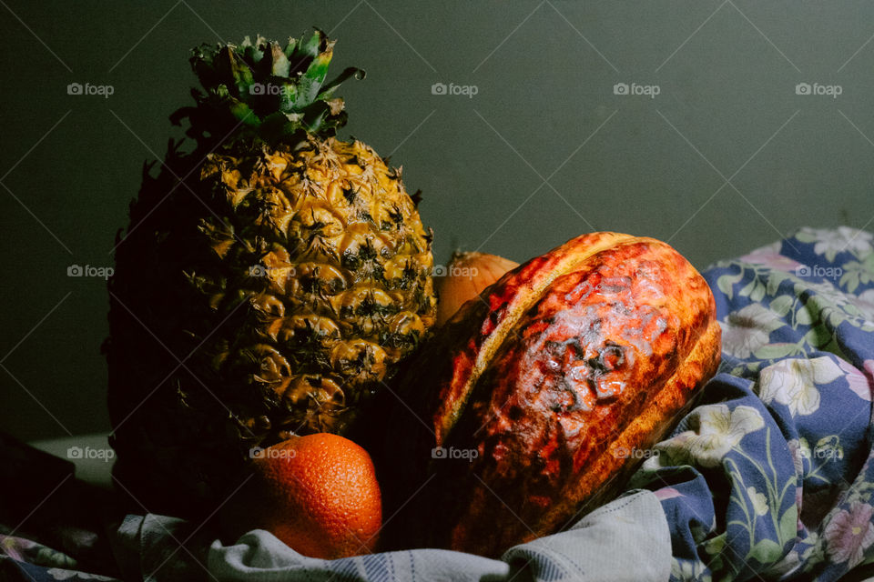 Hawaiian Pineapple and a Cacau Fruit skin with colorful lighting. Details of fruit skin, creamy Bokeh