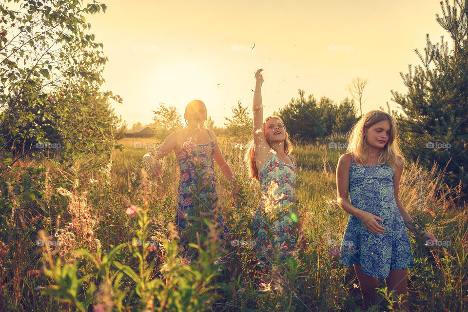 Summer vibes, girls are walking on the hayfield on the countryside