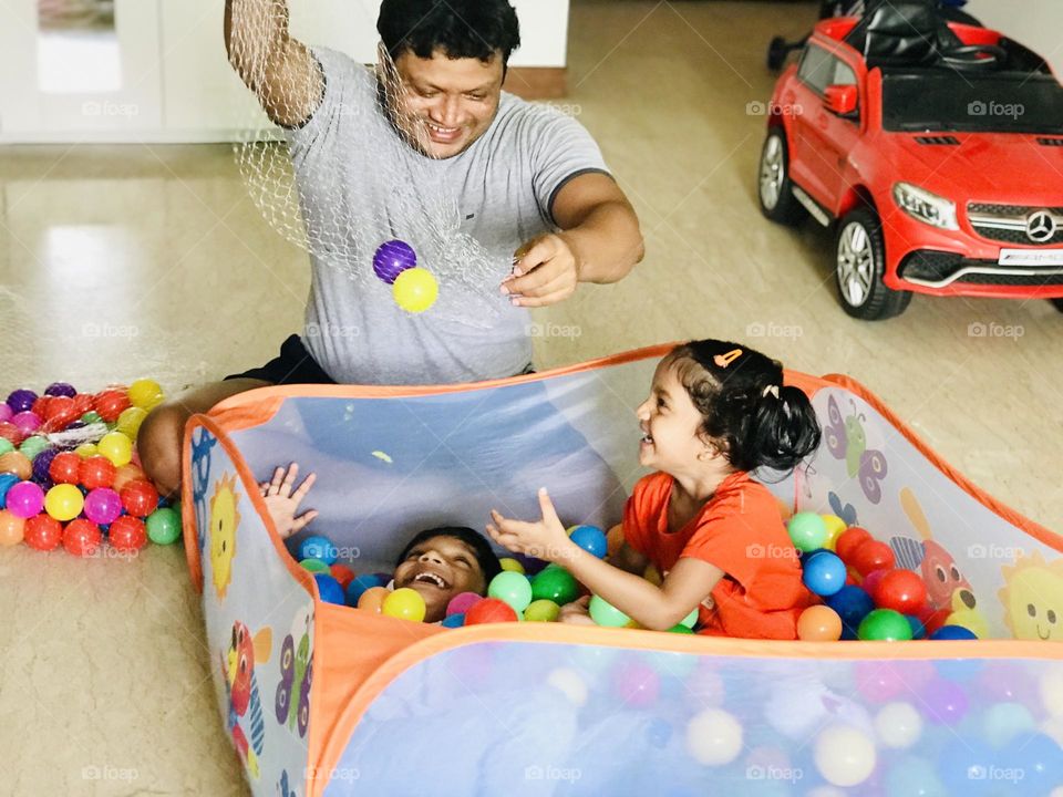 Father had a great fun time with kids by playing with kids in ball pit at home 