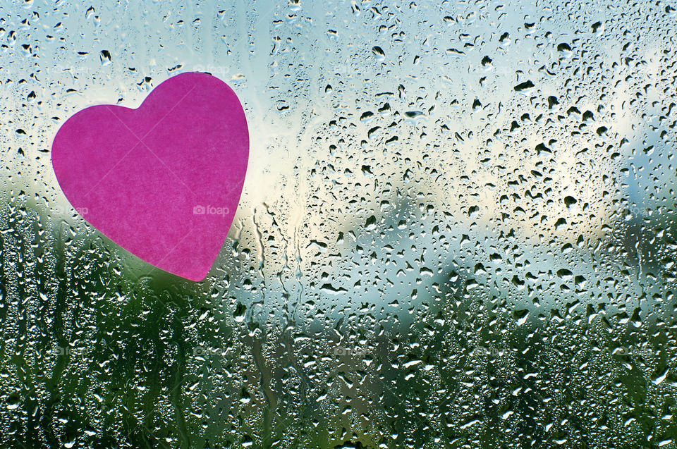 the drops of rain on the window with pink heart sticker