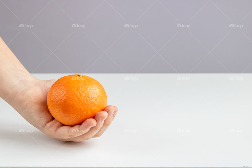 Tangerine fruit in hand of child with copy space.