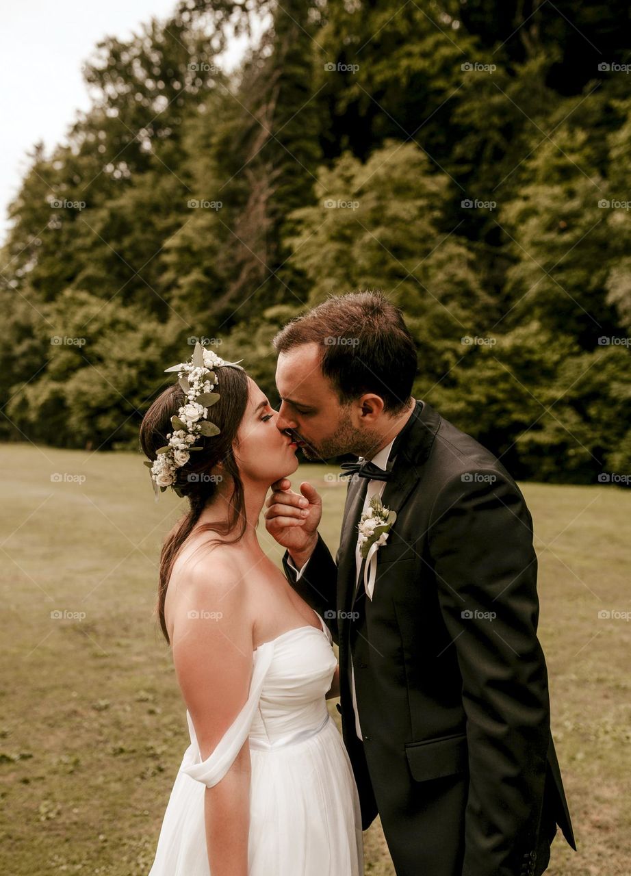 Young newlyweds kissing outdoor on a meadow