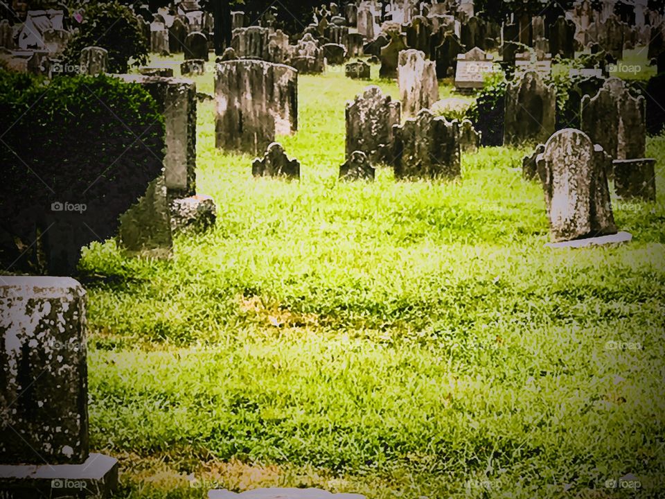 Old cemetery with many old grave stones with patch of green grass in foreground
