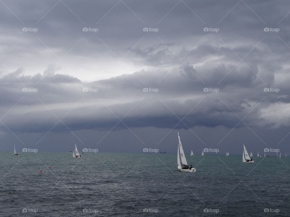 Sailboats sailing against storm clouds
