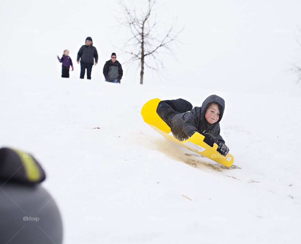 Boy sledding down the hill in winter 