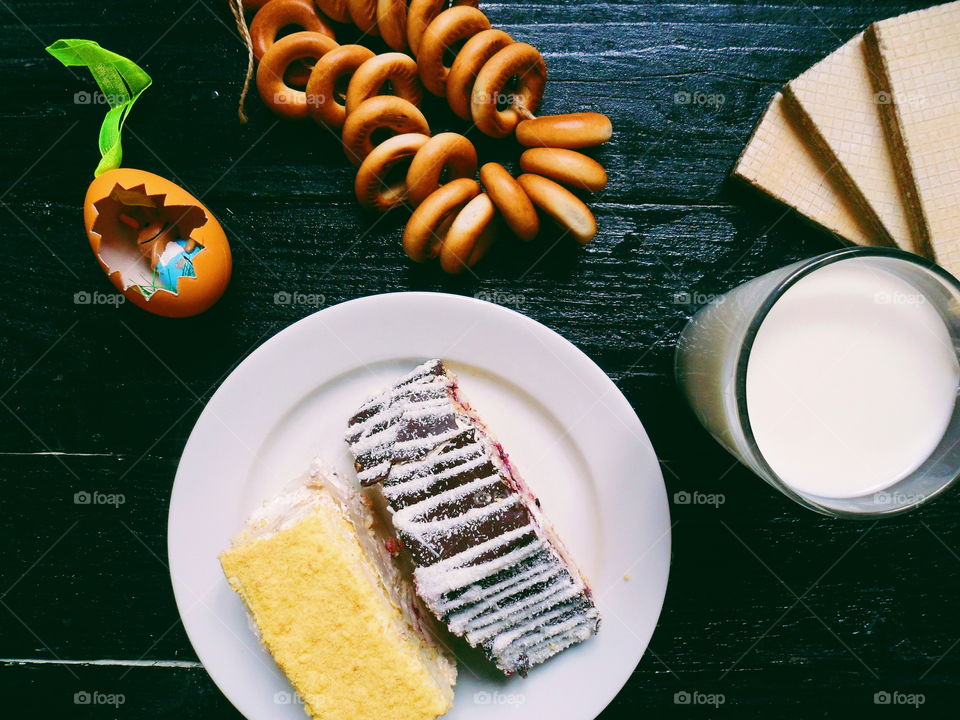 cakes, a cup of milk, bagels and waffles on a black background