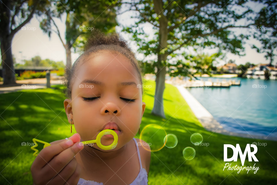 Portrait of cute girl blowing soap bubbles outdoors