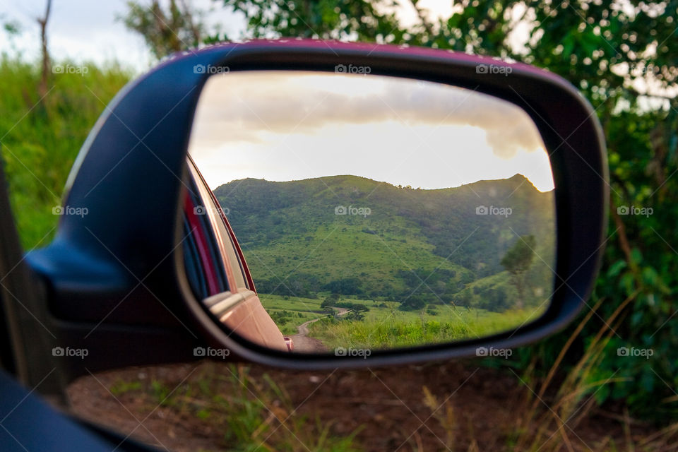 A different view on nature. Image in car mirror looking at the road and green hills. Image from Hluhluwe game reserve Africa.