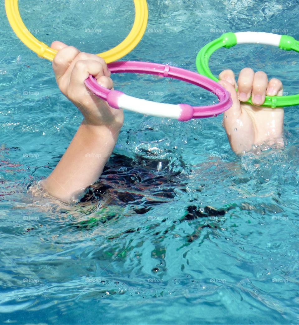 Boy holding up rings in a swimming pool 