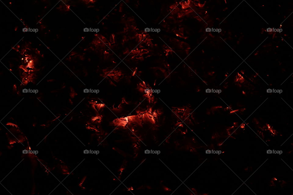 Warm glowing coals from a fire in a cool night.