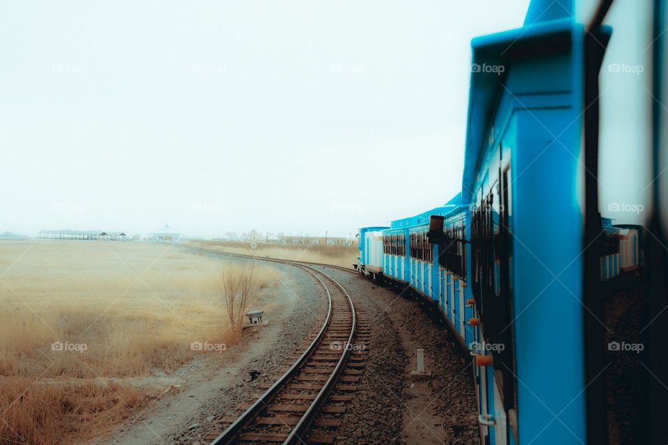 A blue train running on track in a foggy day