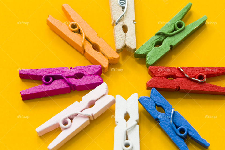 group of multicolored clothespins on an yellow background.  clash of colors concept!