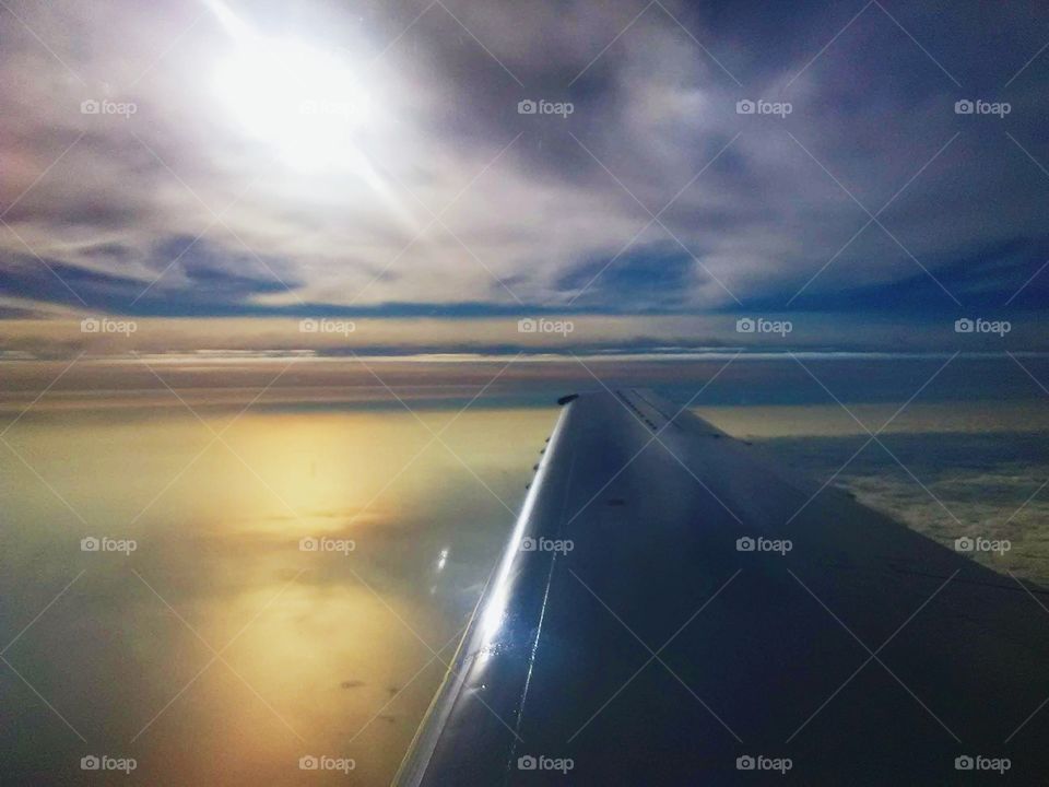between the clouds from a plane with reflection of the sun shining on lake Michigan bottom layer of clouds