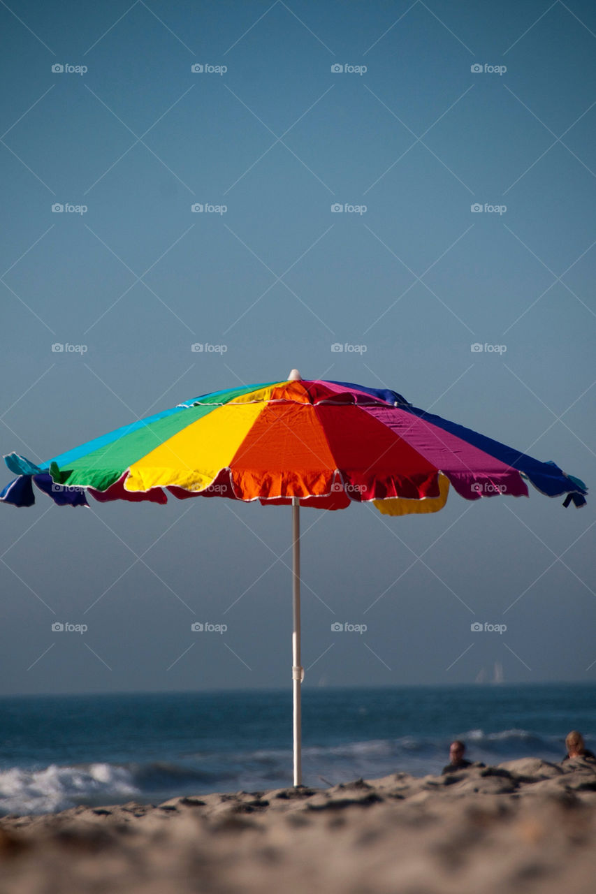 Rainbow colored umbrella on the beach in California