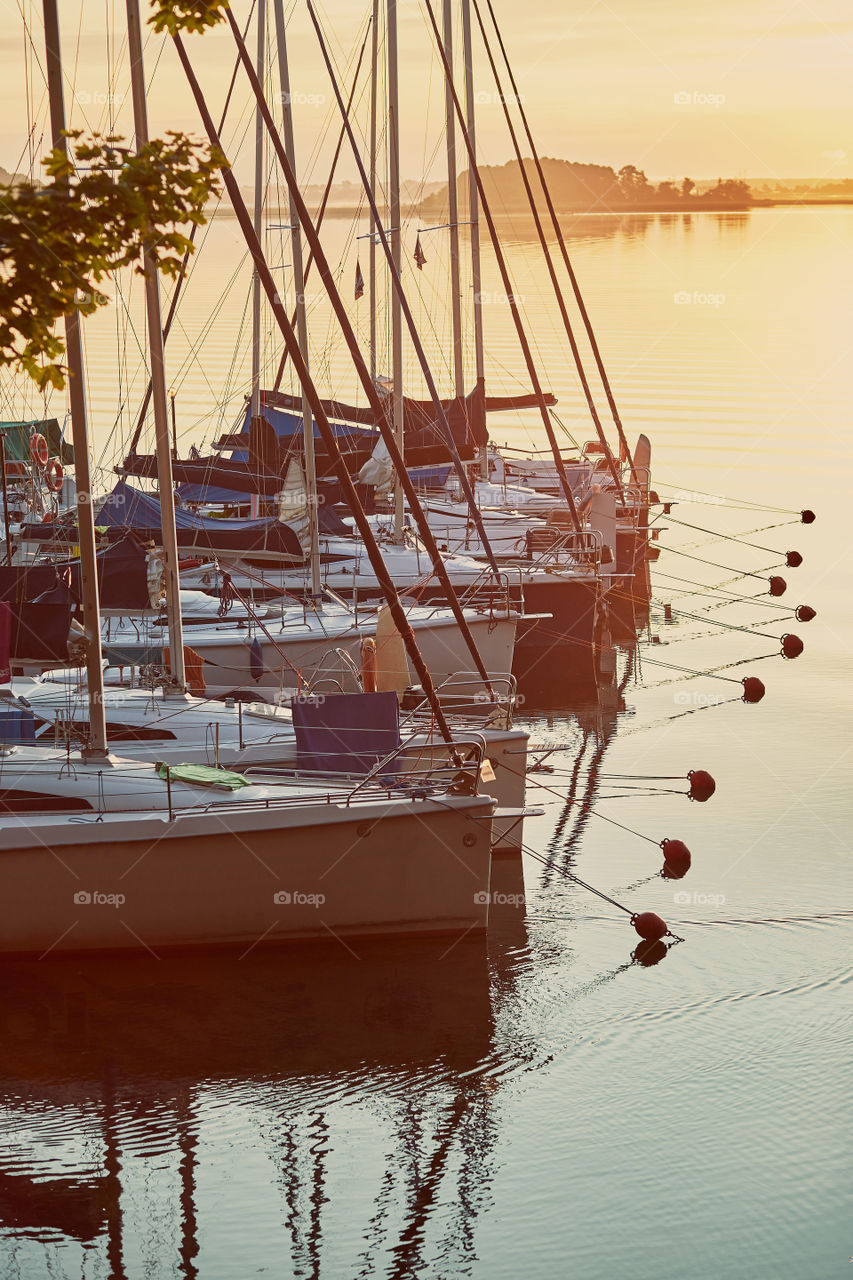 Yachts and boats moored in a harbour at sunrise. Candid people, real moments, authentic situations