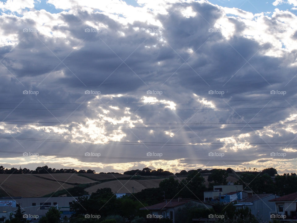Landscape, sky with clouds and sun rays that illuminate the village