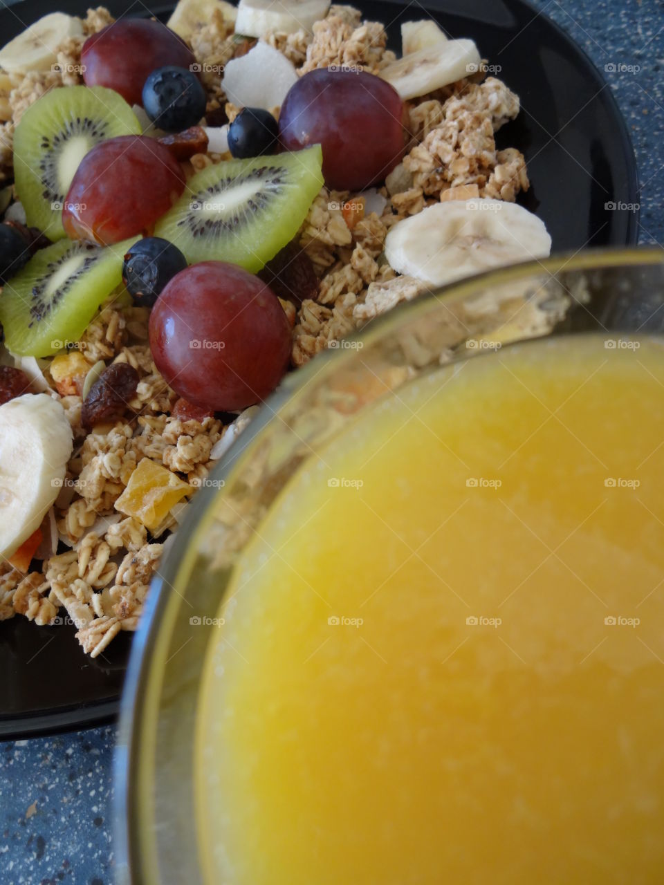 Healthy breakfast of crunchy flakes kiwi, banana, grapes, berries, raisins and fresh orange juicy drink