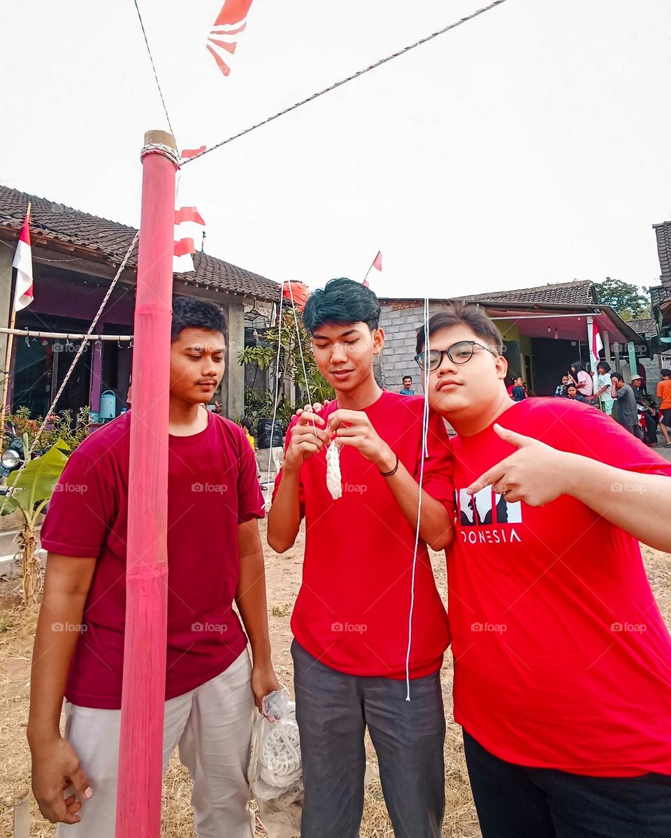 Portrait of three adult men putting up crackers for a competition on Indonesia's independence day