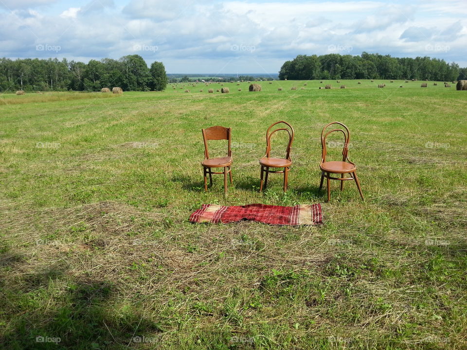 Three old chairs and a rug on a field in Russia