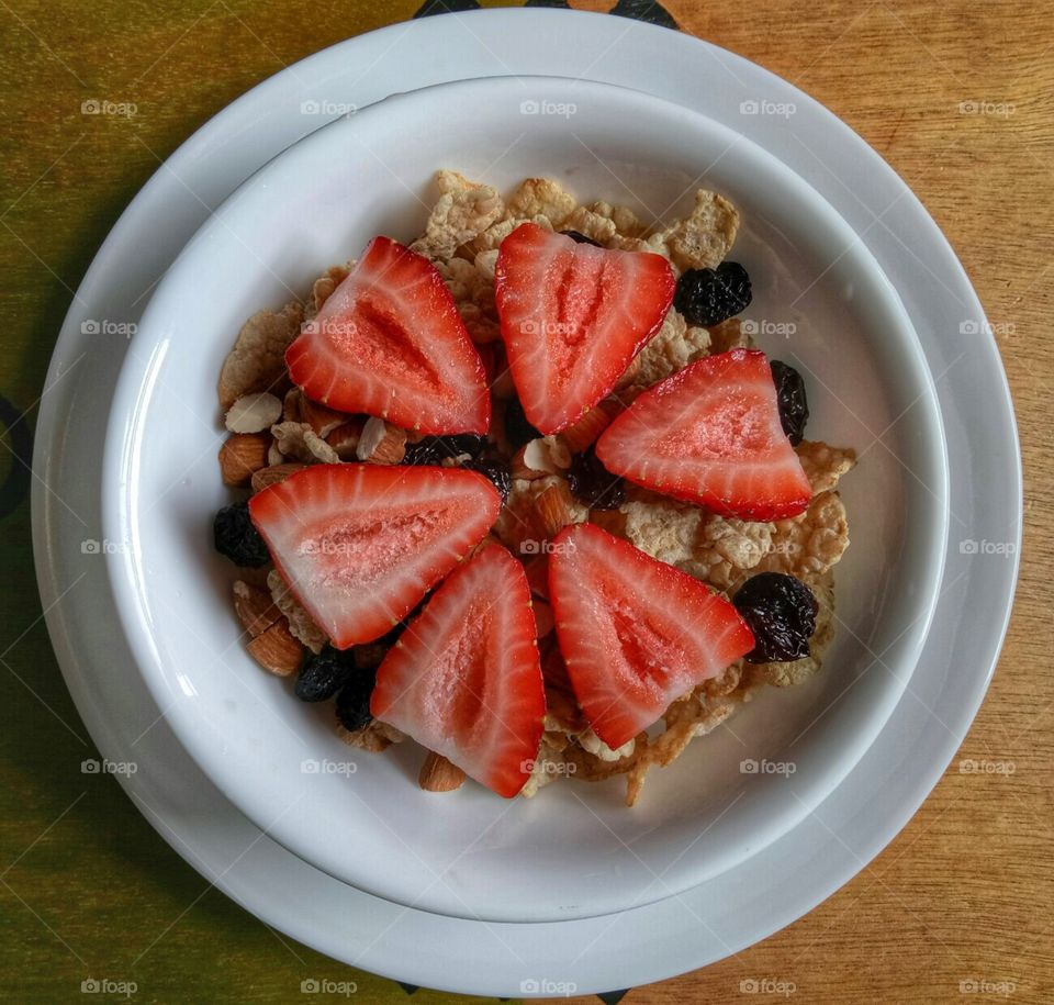 Cereal for breakfast with high fiber with strawberries, raisins and almonds with milk. 