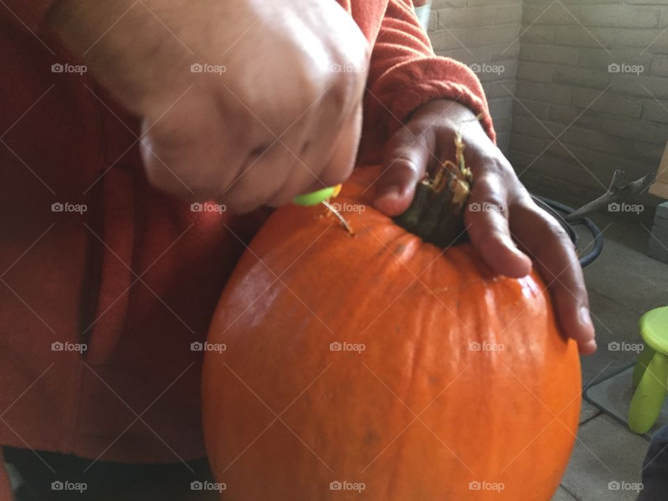 Strong hands at work, carving pumpkin 