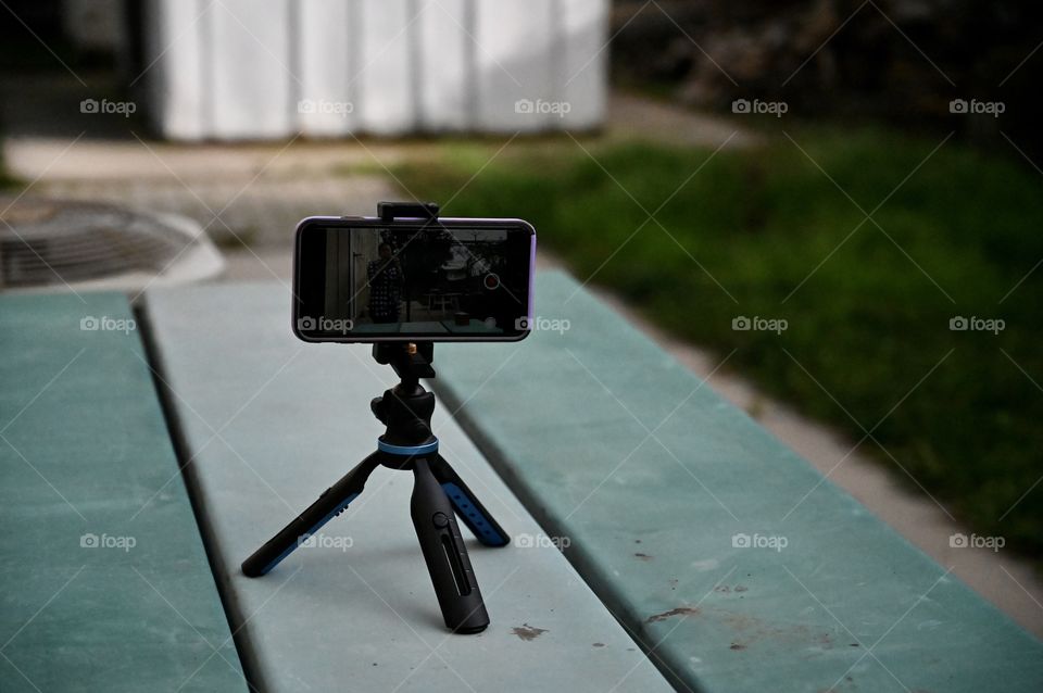 Mobile phone on the tripod on the table at the backyard