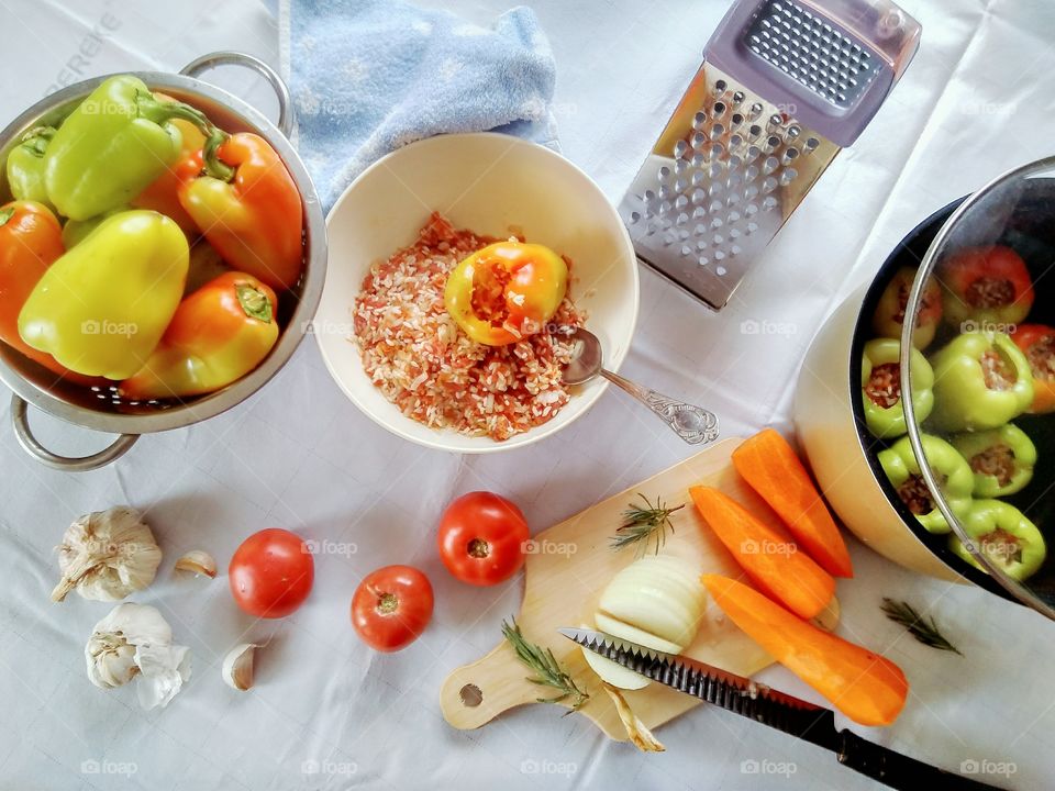 the process of cooking stuffed peppers with meat and rice, cutting onions and carrots for broth